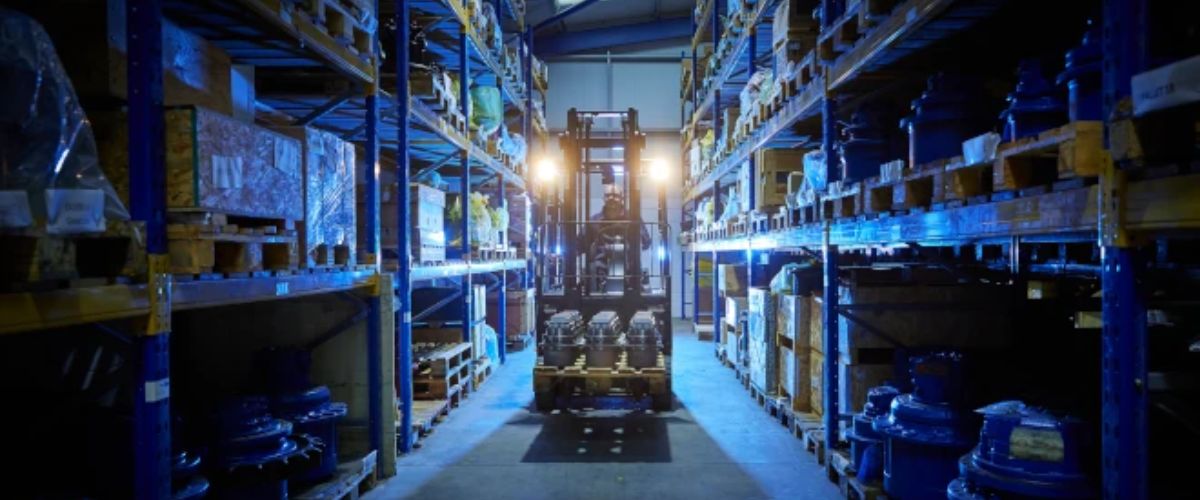 Forklift truck with lights on moving stock inside Plant Parts warehouse